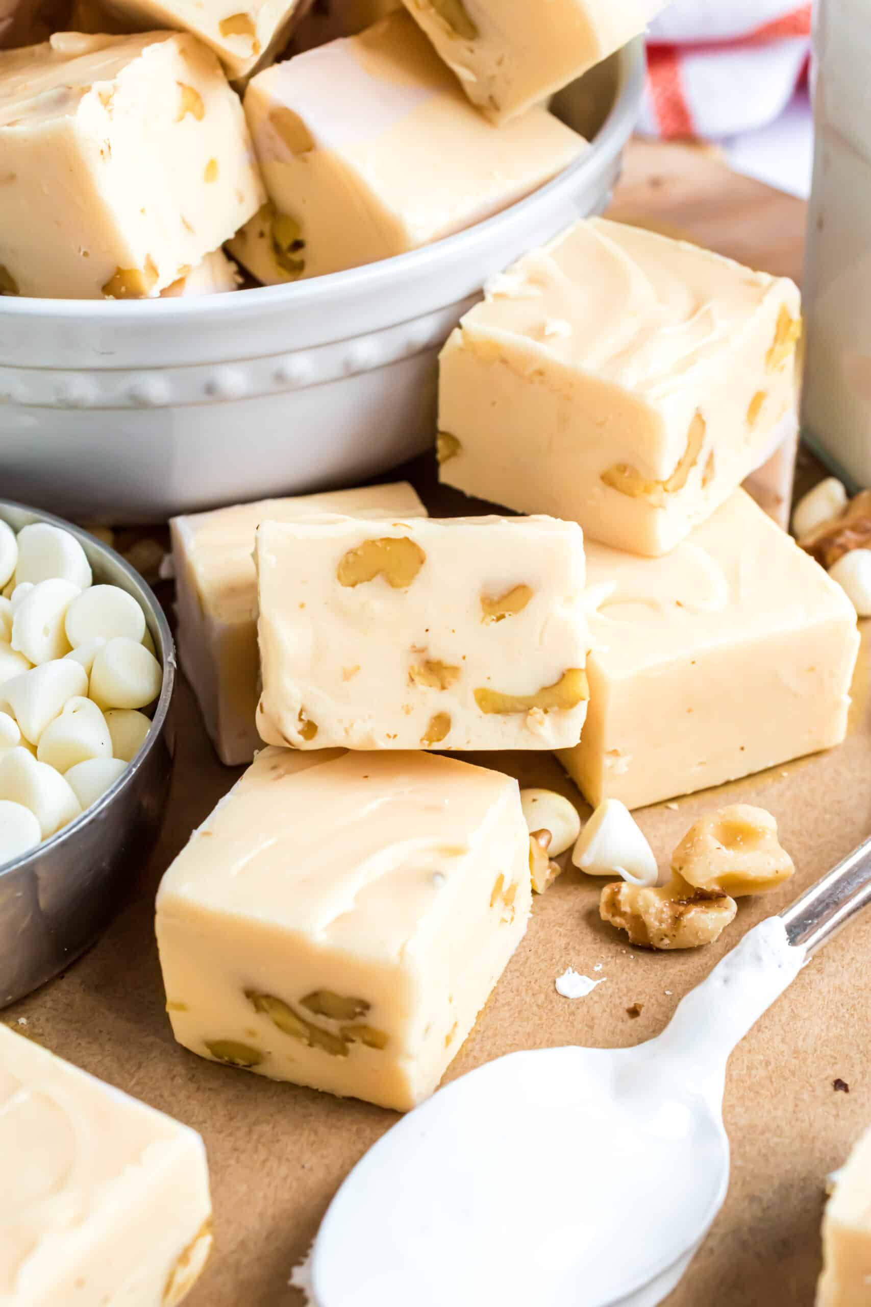 Pieces of maple walnut fudge on a parchment paper with spoonful of fluff.