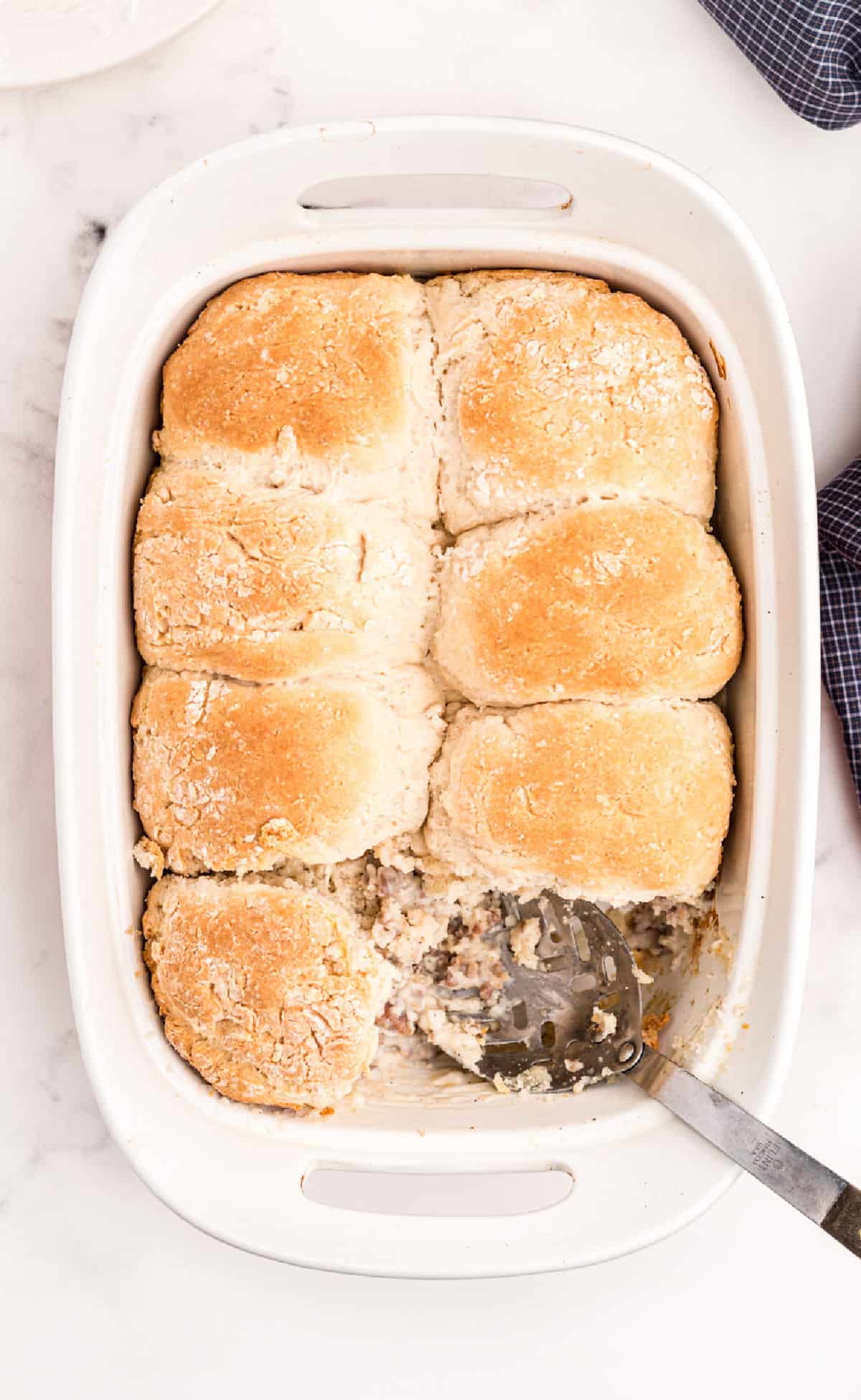 Sausage and gravy casserole topped with homemade biscuits in 13x9 baking dish.