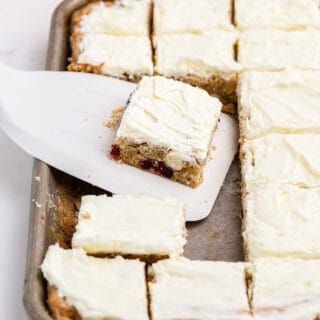 Slice of cookie bar with cranberry orange and frosting.