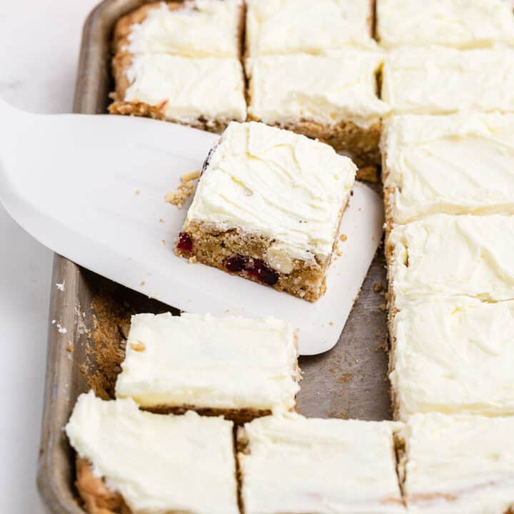 Slice of cookie bar with cranberry orange and frosting.