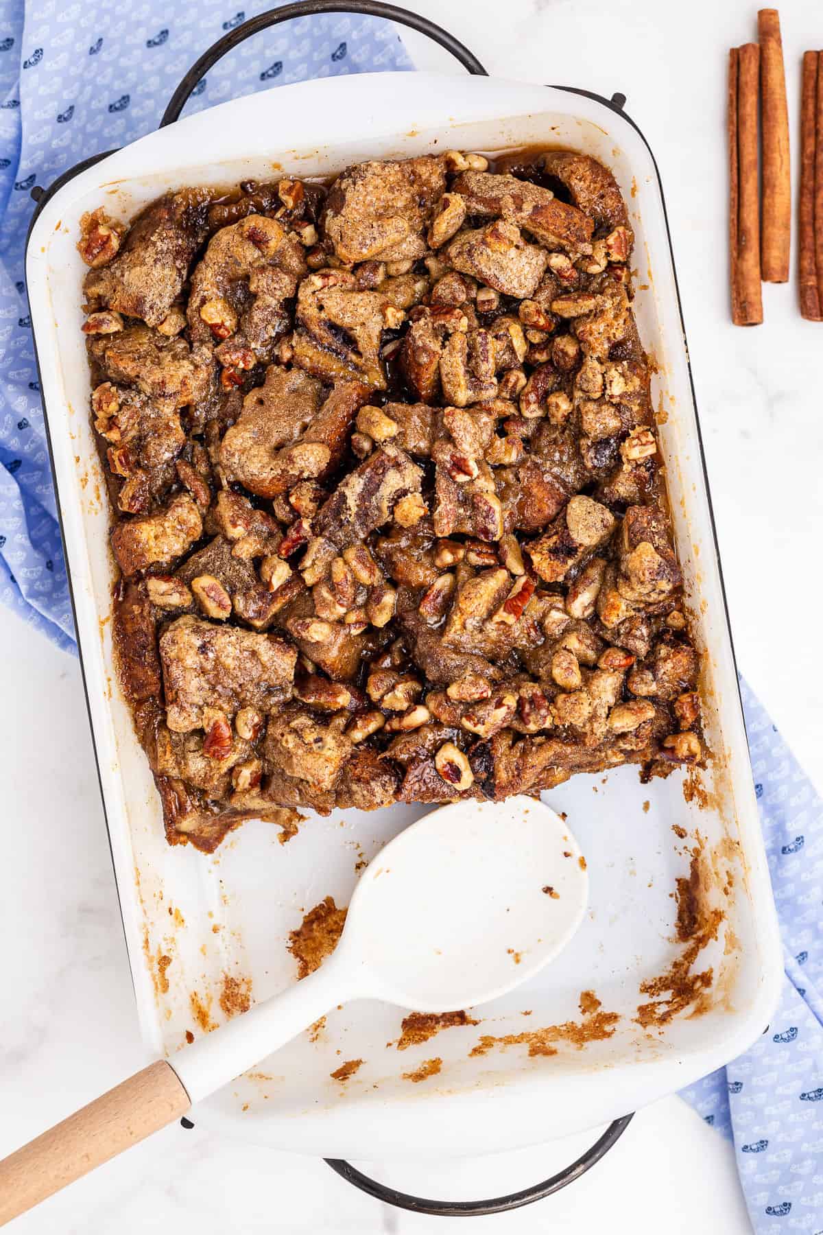 French toast casserole in a white baking dish with several scoops removed.