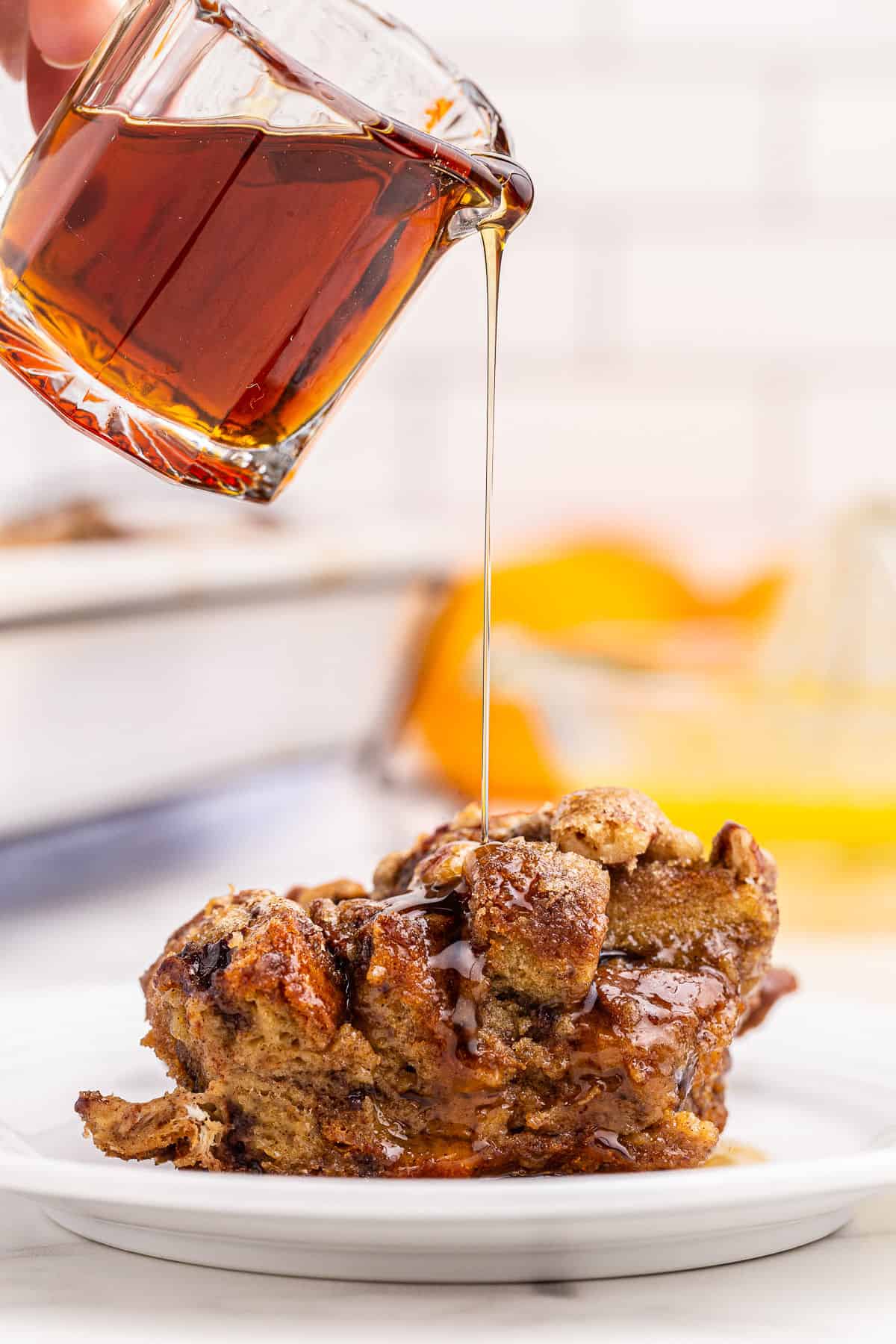 Scoop of french toast casserole with syrup being drizzled on top.