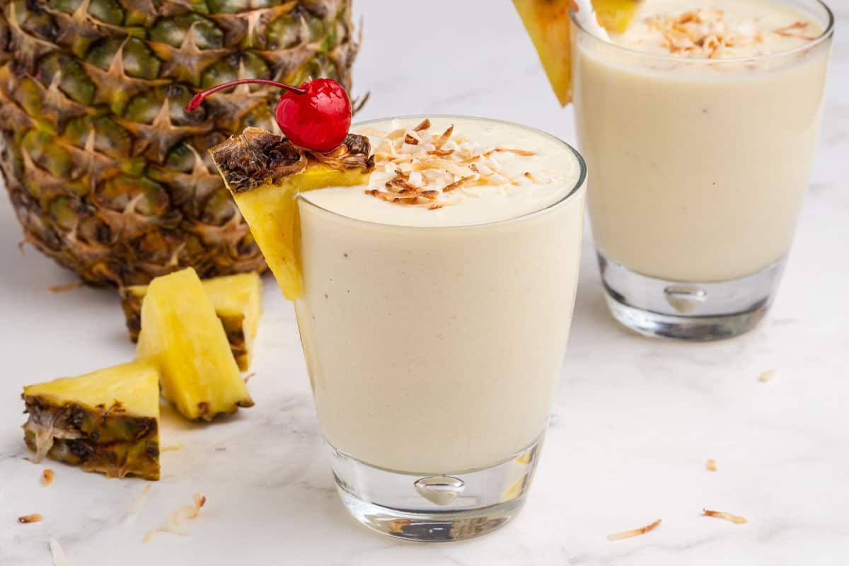 Pina colada smoothie with cherry and pineapple garnish.