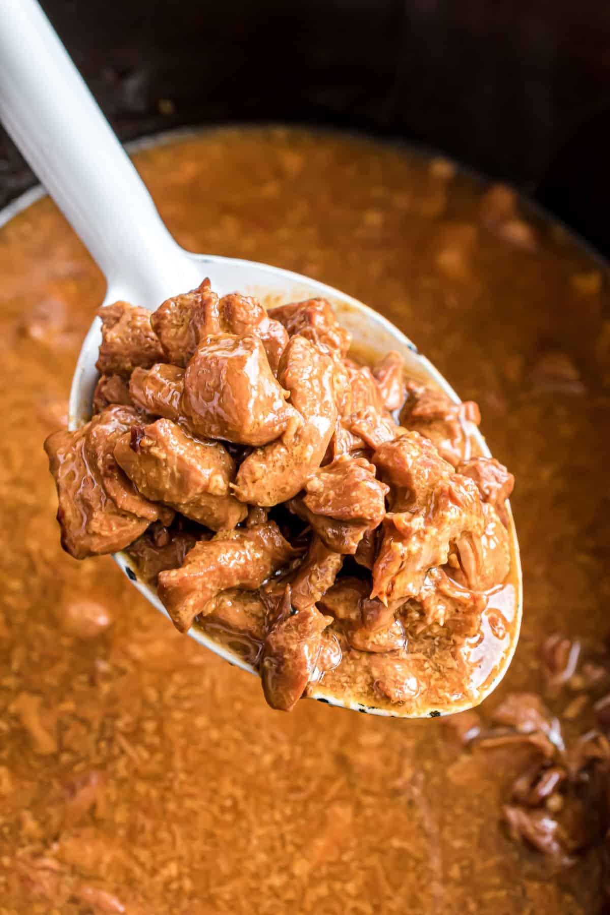 Orange chicken spooned out of the slow cooker.