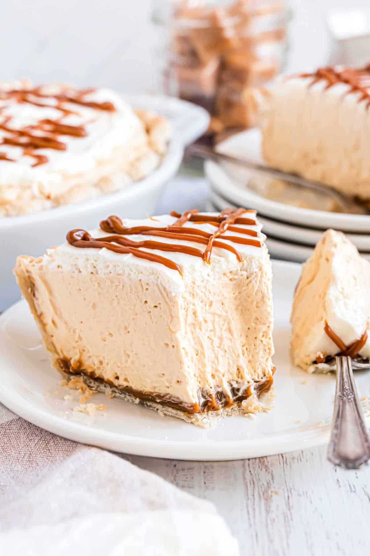 Slice of caramel cream pie with a bite taken out.