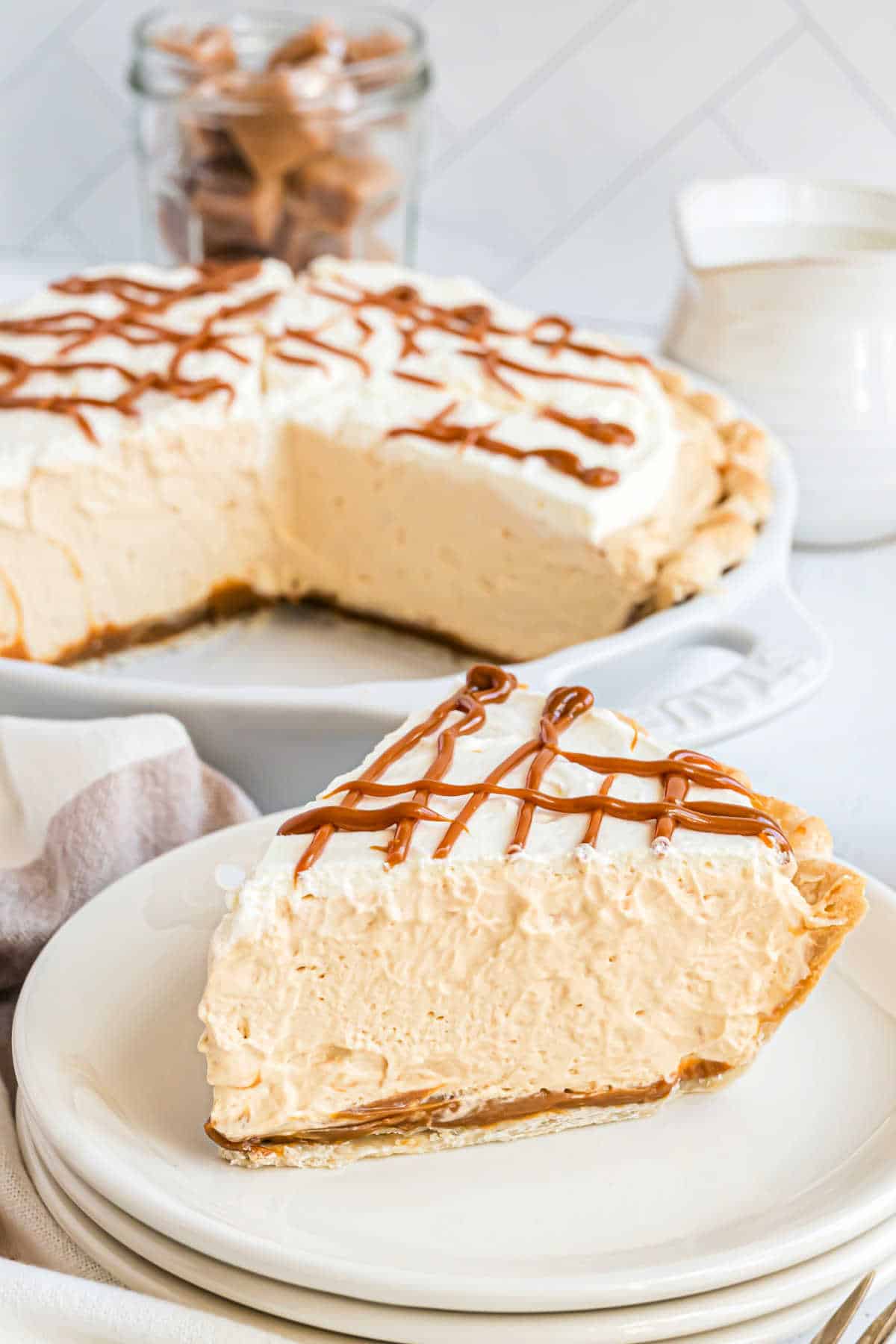 Slice of caramel pie on a stack of white plates.