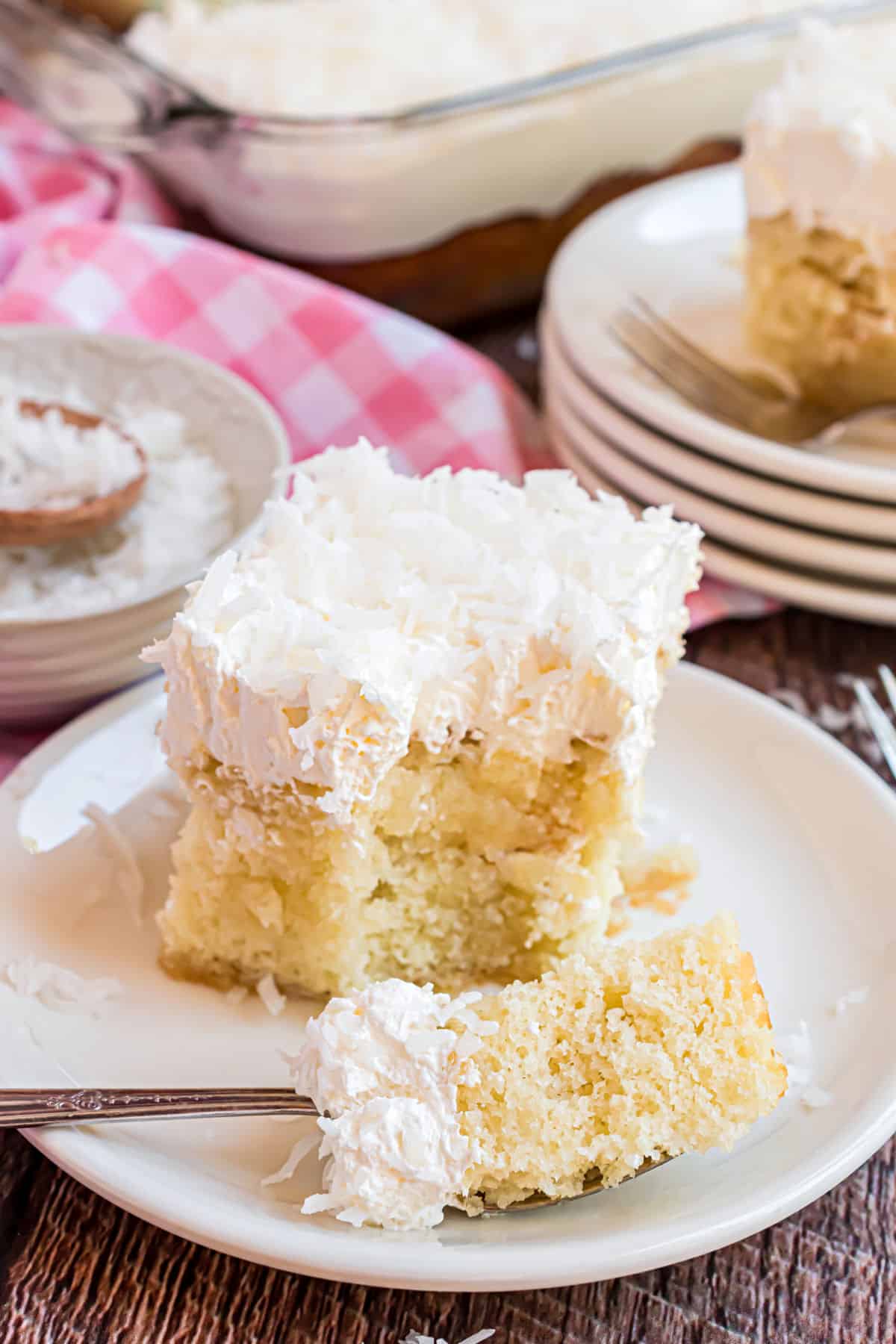 Slice of coconut cake with a bite taken out.