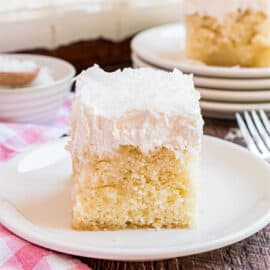 Slice of coconut cake on a white plate.