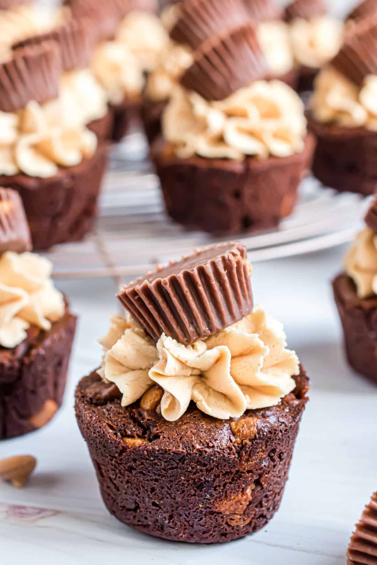 Brownie bites with peanut butter chips, peanut butter frosting and reese's cups on top.