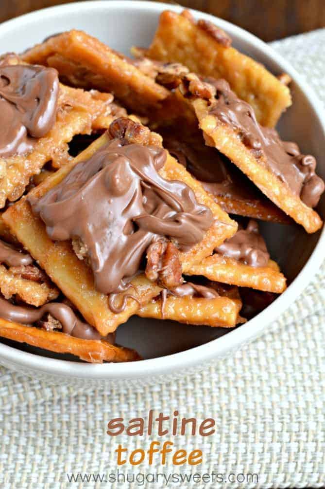 Toffee made with saltine crackers and topped with pecans and chocolate, in a bowl.