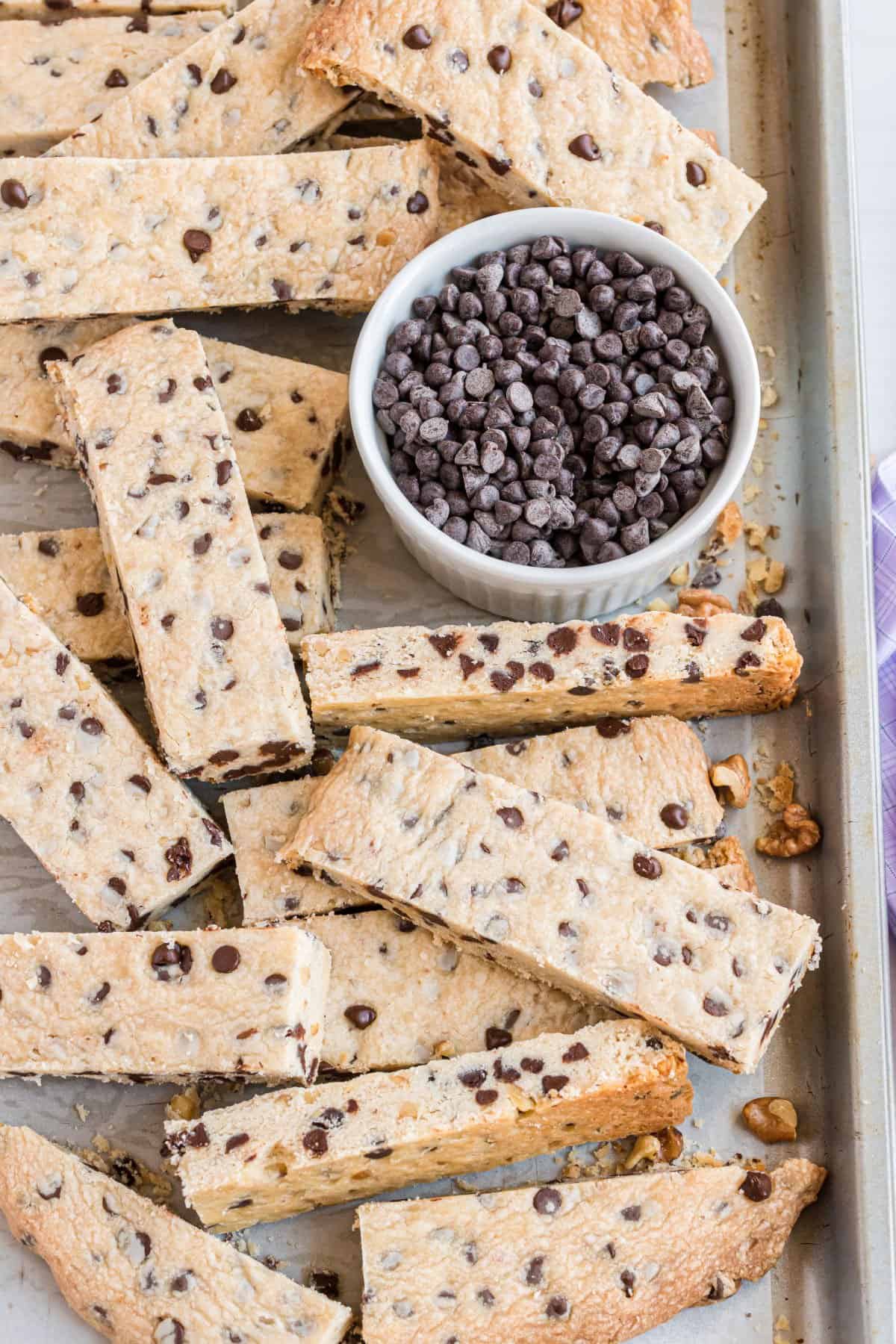 Stacks of shortbread cookie sticks with chocolate chips on a cookie sheet.