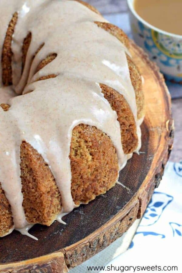 Zucchini bundt cake with a cinnamon glaze on a wooden cake platter.