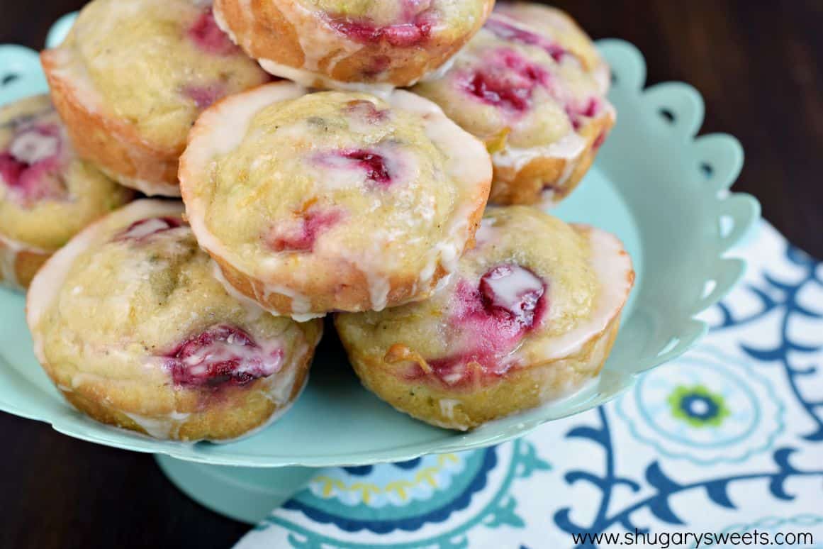 Cranberry zucchini muffins with a glaze stacked on a cake platter.