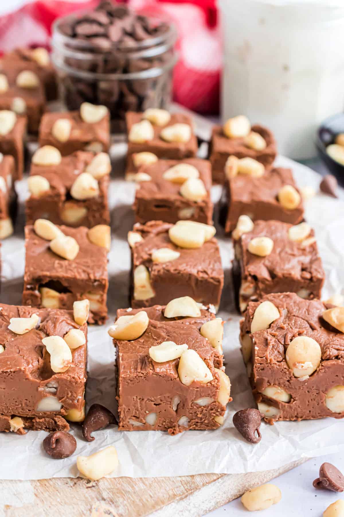 Pieces of chocolate fudge with macadamia nuts cut on a piece of parchment paper.