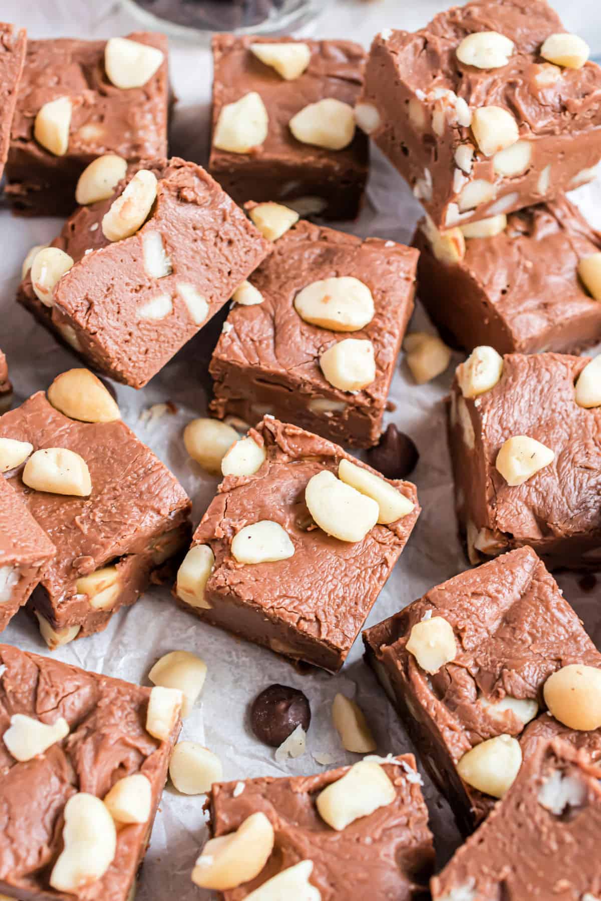 Pieces of macadamia nut fudge stacked on parchment paper.