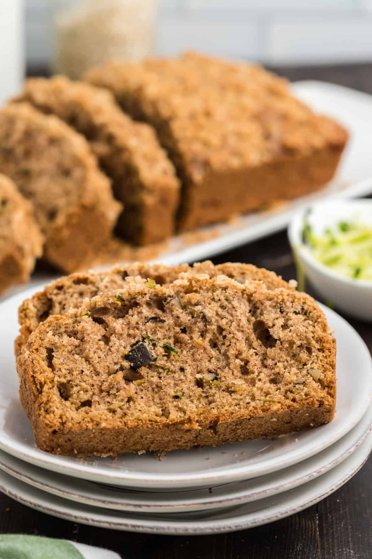 Zucchini bread slices ona  stack of white plates.