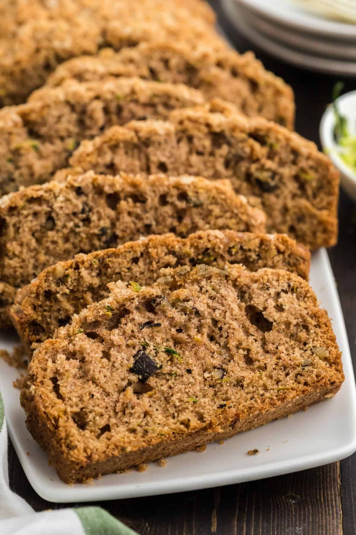 Streusel topped zucchini bread sliced on a white serving plate.