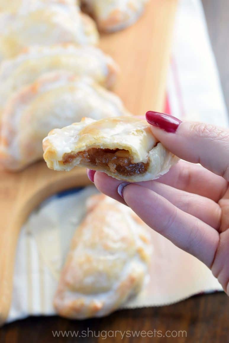Glazed apple hand pies being held up after taking a bite.