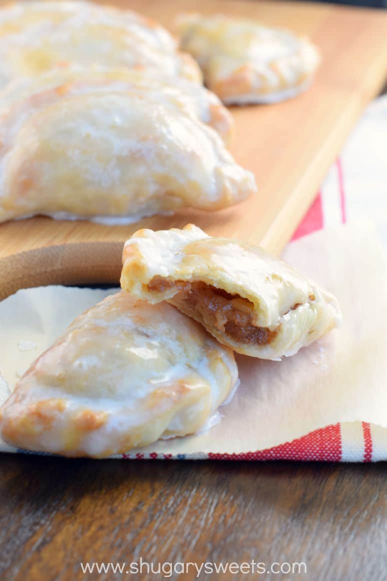 Hand pies with apple filling on a piece of parchment paper, cut open to see the inside.