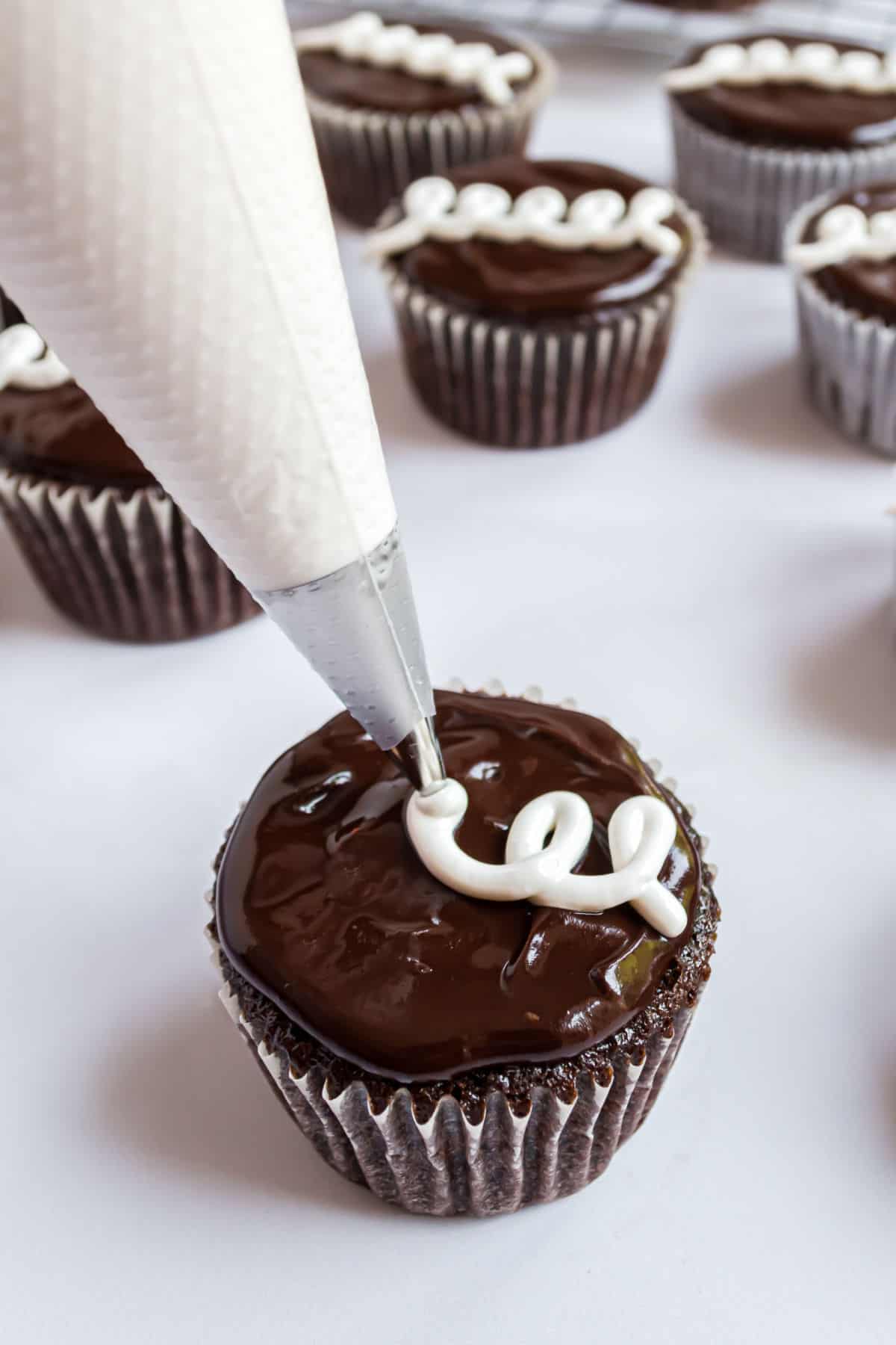 Icing being piped onto a homemade hostess cupcake.