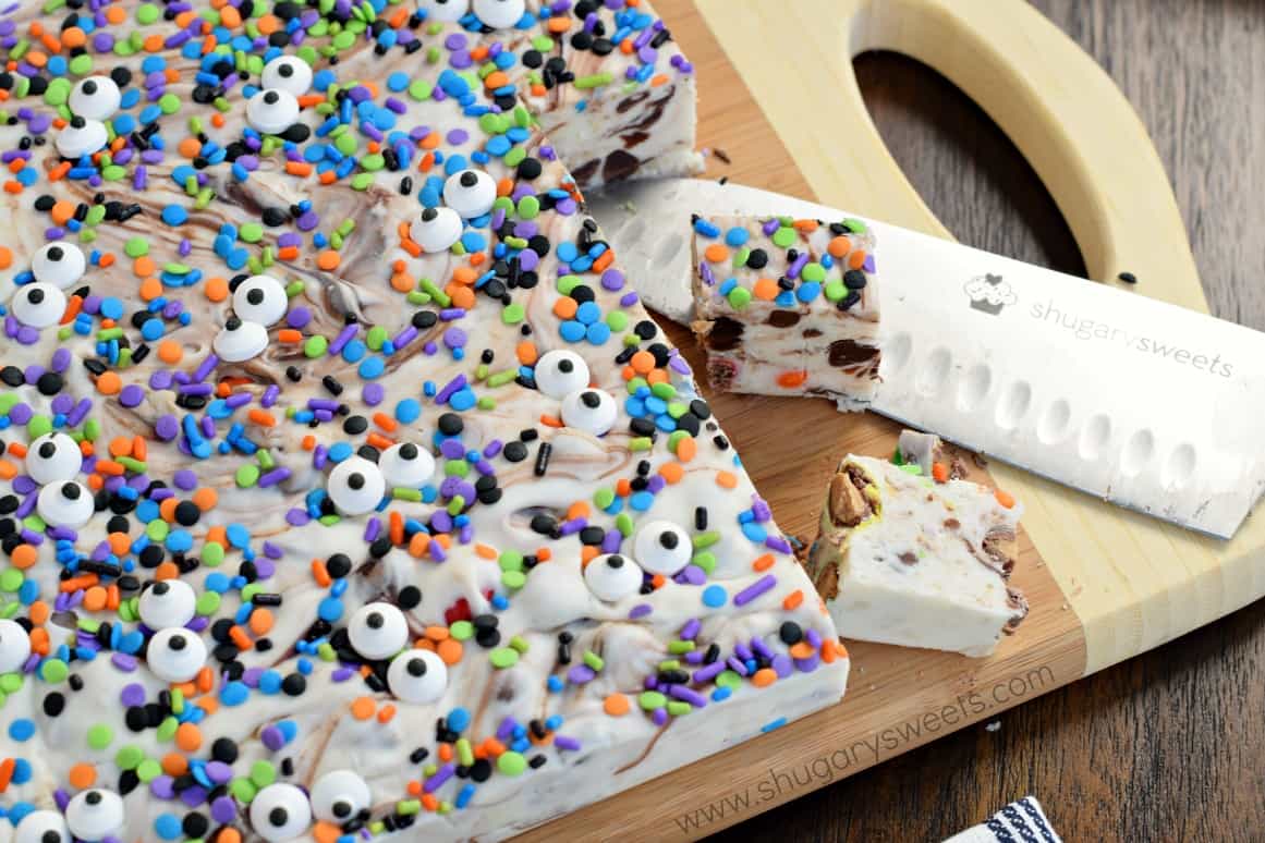 Cutting board with knife and pieces of monster cookie dough fudge being cut.