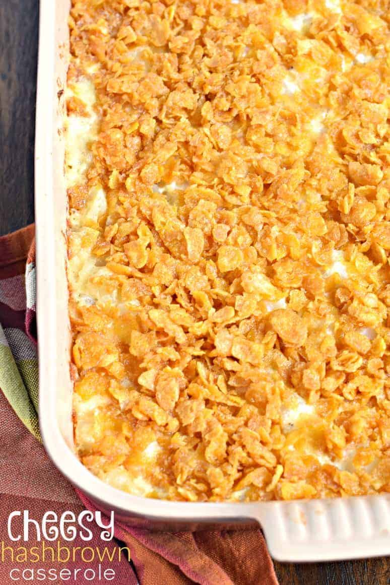 This Cheesy Hashbrown Casserole makes an appearance at all family gatherings. So easy and delicious and perfect for a crowd! #holidayrecipe #hashbrowns Hashbrown casserole with corn flakes in a casserole dish.