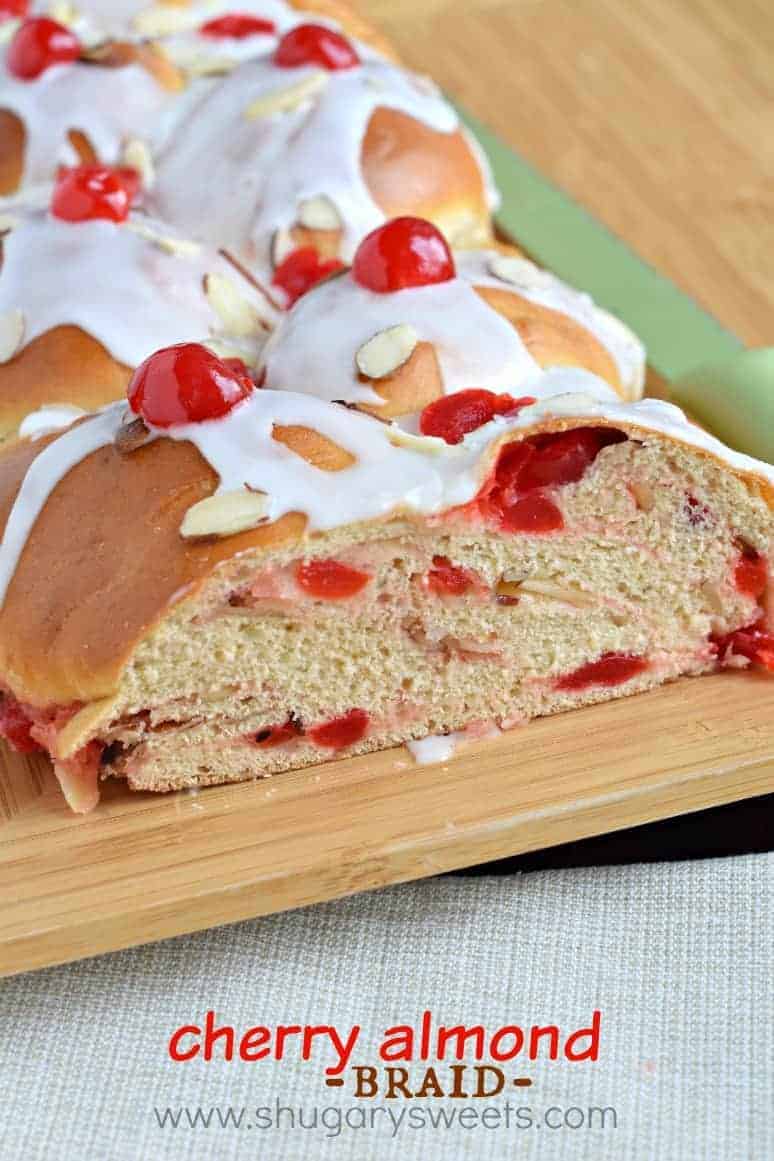 Adding this sweet Cherry Almond Braid to your holidays is a delicious idea! Sweet yeast bread stuffed with cherries and almond glaze! Loaf of cherry almond bread with almond glaze on wooden platter.