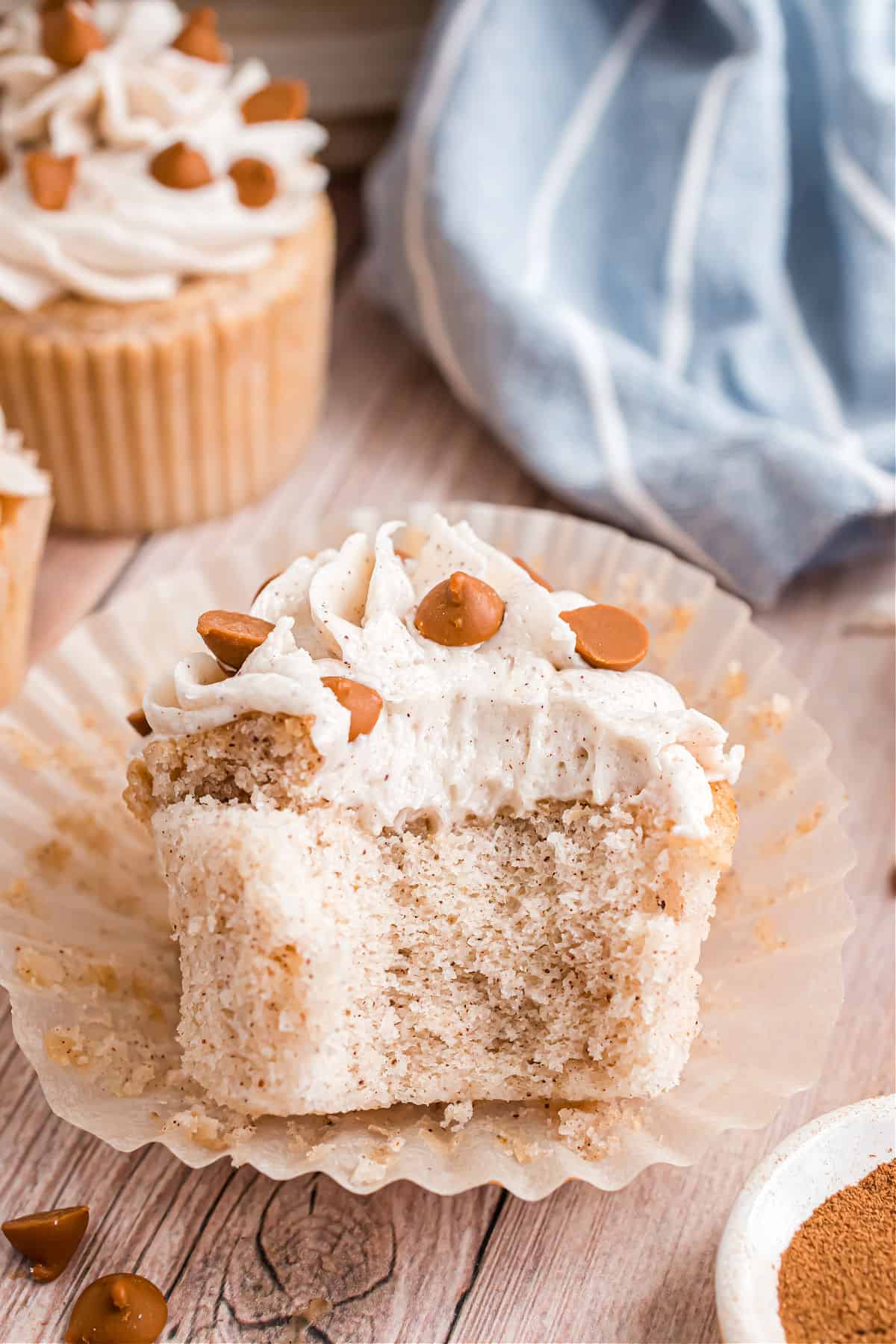 Spice cupcake with cinnamon frosting with a bite taken out.