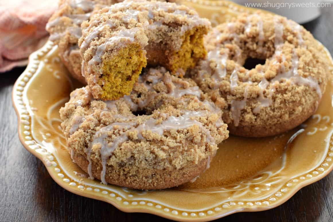 Pumpkin streusel topped donuts with glaze on a yellow plate.