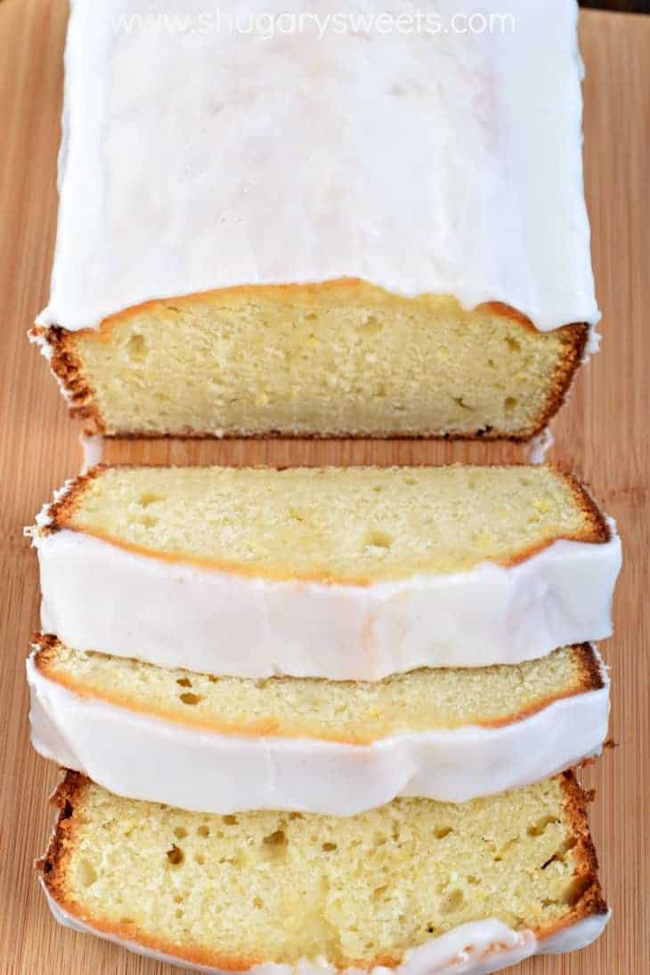 Loaf of lemon bread on a wooden cutting board, topped with vanilla glaze.