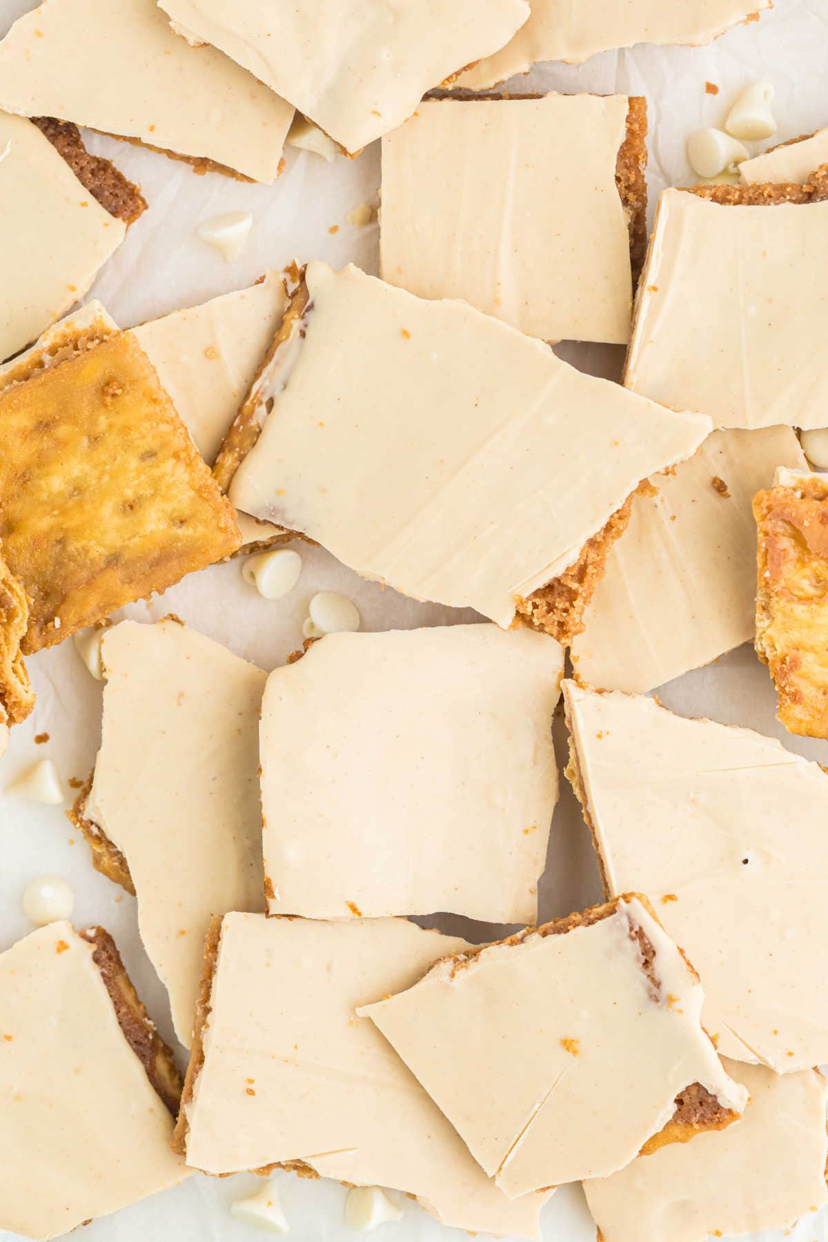 Rectangular pieces of peanut butter cracker toffee bark with a white chocolate topping, arranged on a white surface.