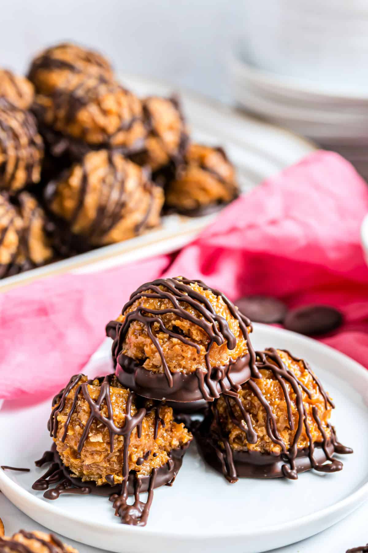 Three coconut and chocolate candies stacked on a white plate.