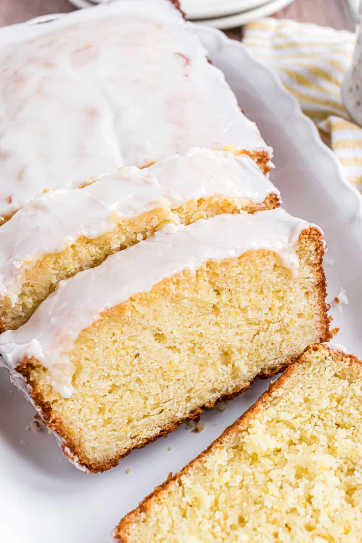 Loaf of lemon bread with lemon icing on top, sliced and plated.