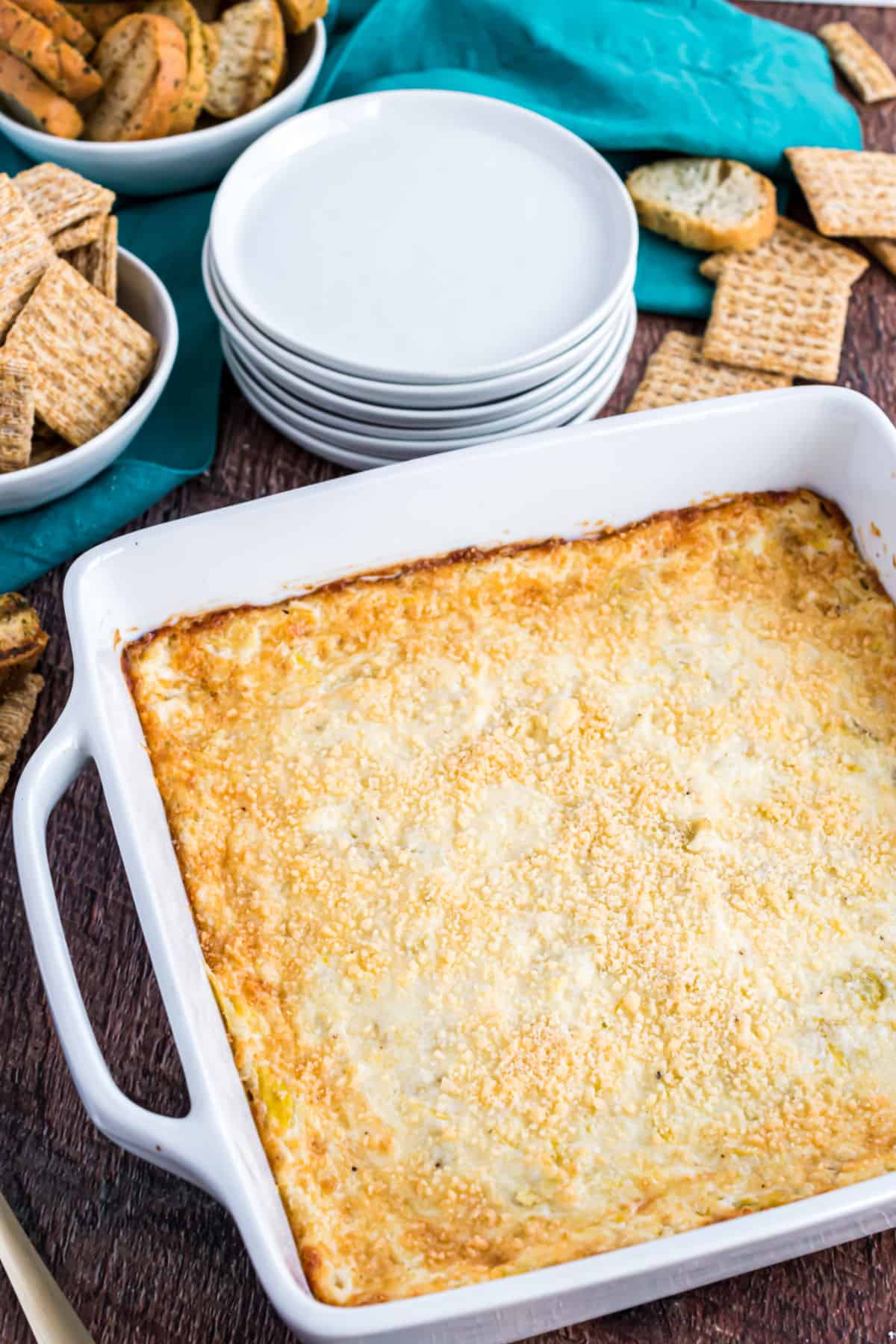 Artichoke dip baked in a square dish and served with triscuits.