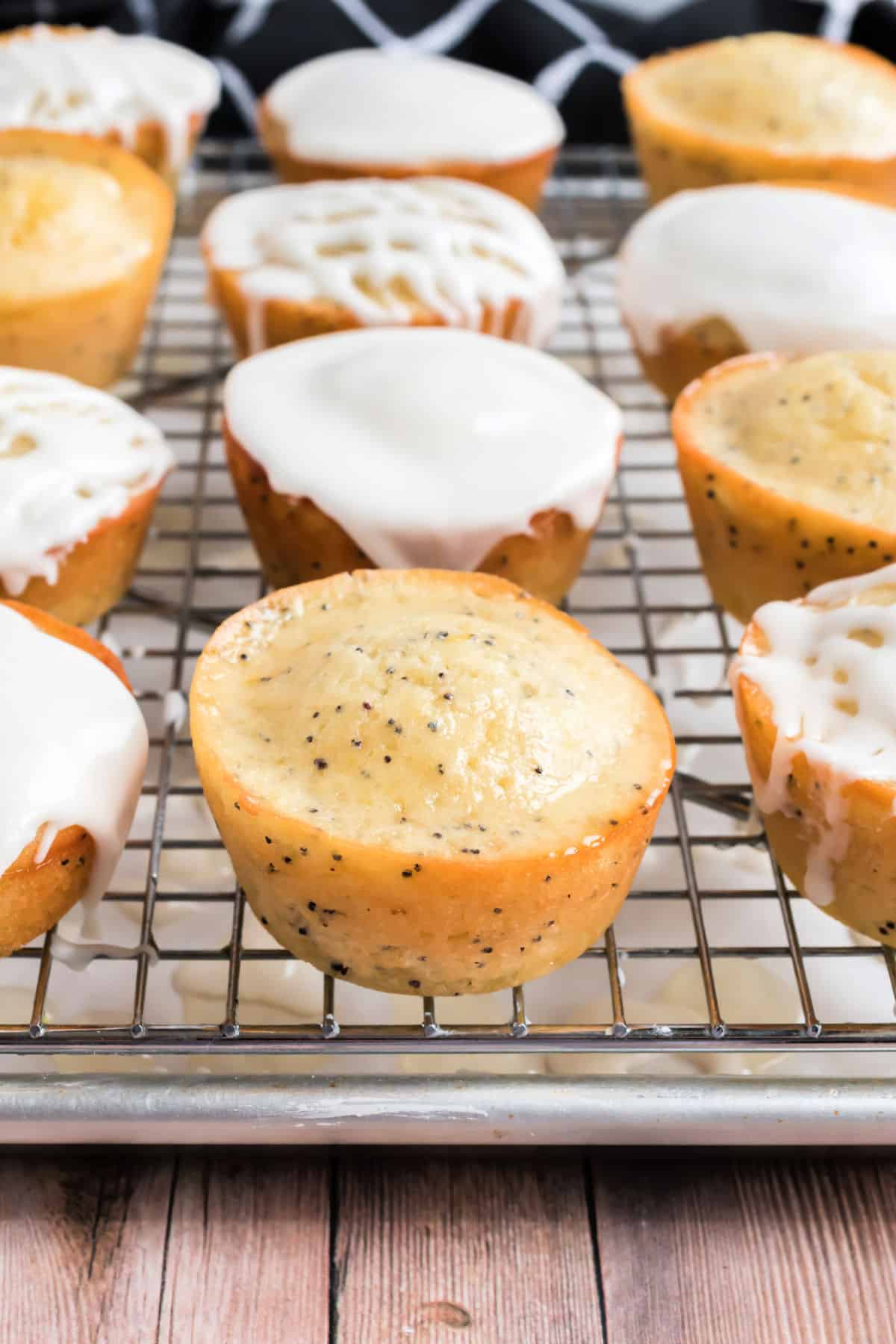 Lemon poppy seed muffins topped with a glaze and icing on a wire cooling rack.