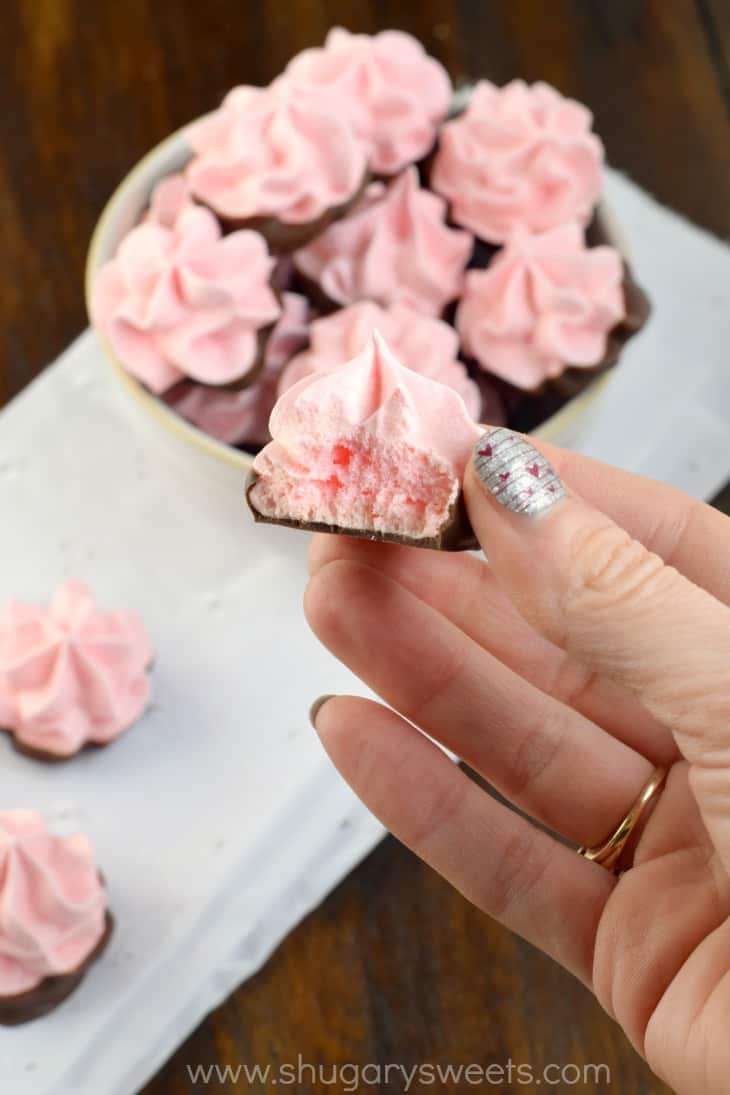 Bite taken out of a chocolate dipped strawberry meringue cookie.