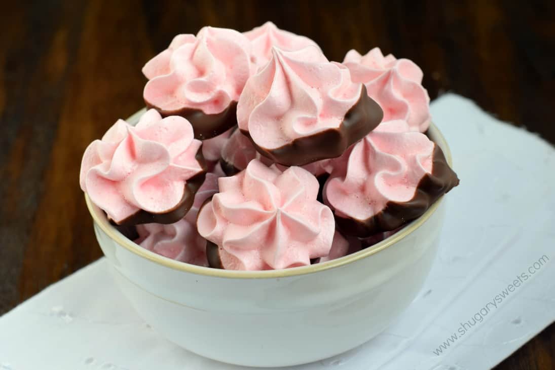 Strawberry meringues dipped in chocolate and served in a white bowl.
