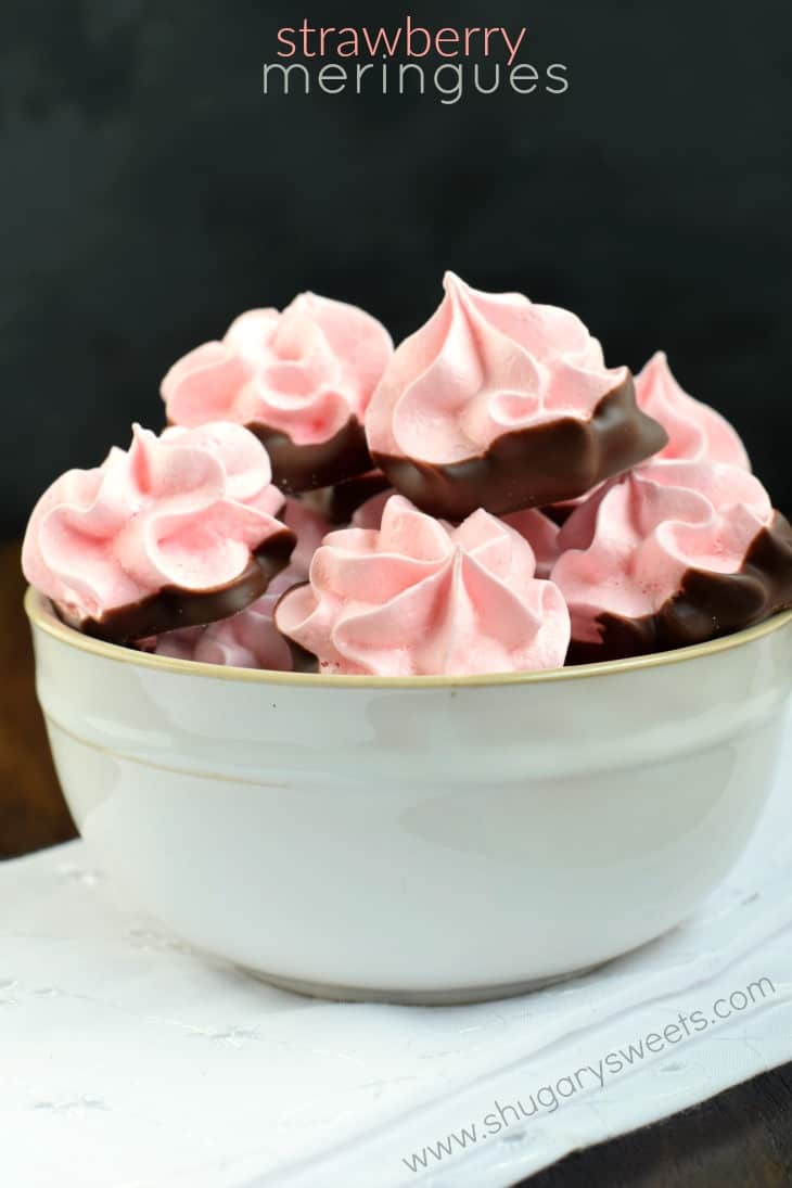 Delicious, festive, melt in your mouth Strawberry Meringues dipped in chocolate! My favorite cookie recipe! Off white bowl filled with chocolate dipped strawberry meringue cookies.