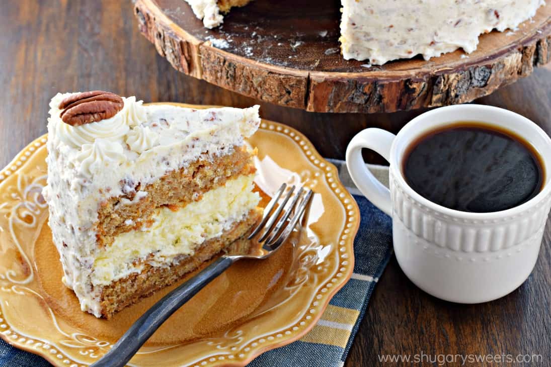 Carrot Cake Cheesecake Cake with cream cheese frosting and pecans on a yellow plate with mug of coffee.