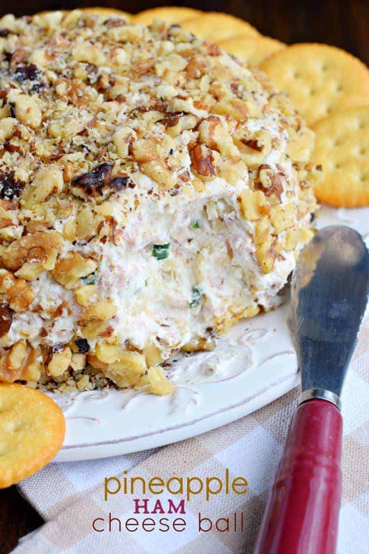 Cheese ball on a serving plate with ritz crackers.
