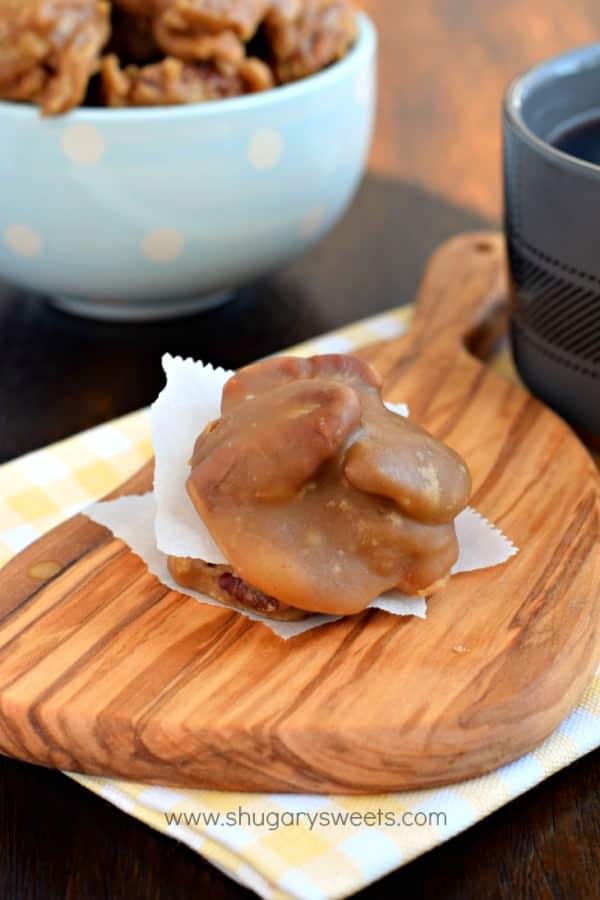 Cutting board with stack of pecan pralines. Blue bowl filled with pralines in background.