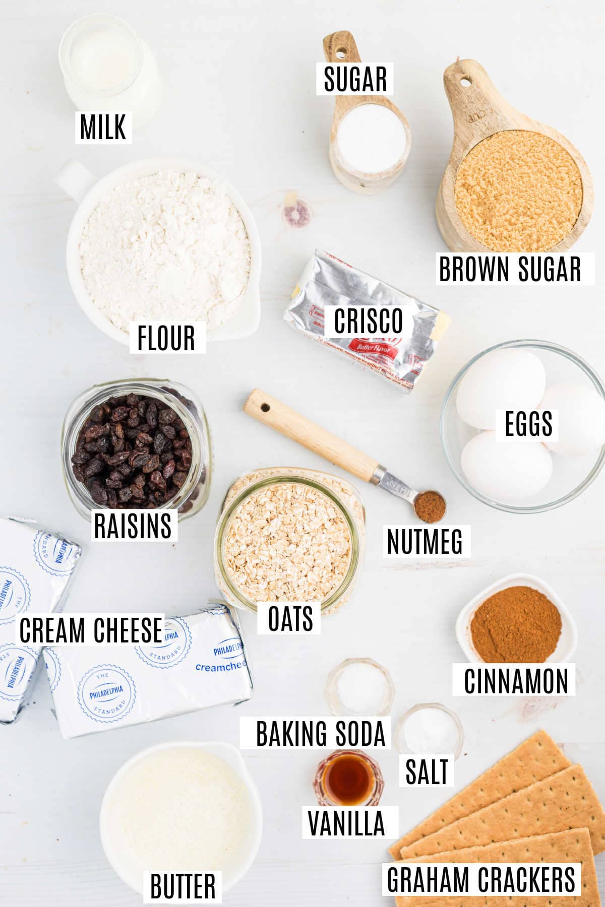 Various baking ingredients labeled, including milk, sugar, brown sugar, flour, eggs, oats, spices, butter, and cream cheese—everything you need to bake delicious oatmeal raisin cookie cheesecake bars.