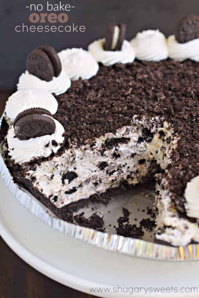Oreo cheesecake topped with oreo crumbs in a pie plate with one slice removed.