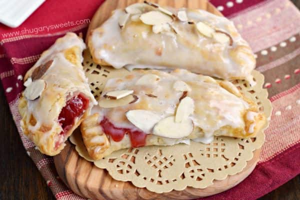 Easy, baked Cherry Almond Hand Pies! A flaky crust with a cherry almond pie filling, dipped in a sugary glaze and topped with sliced almonds. The perfect dessert!