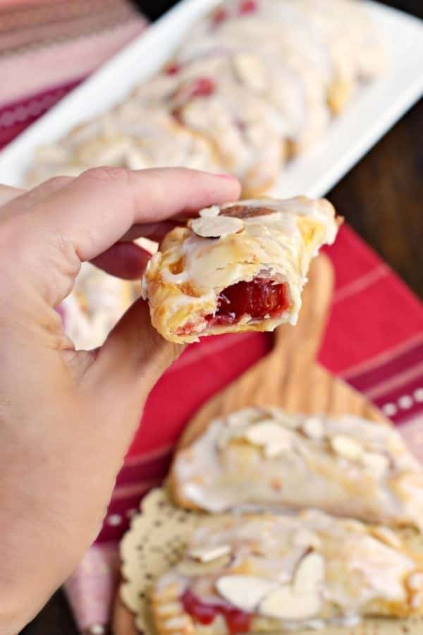 Easy, baked Cherry Almond Hand Pies! A flaky crust with a cherry almond pie filling, dipped in a sugary glaze and topped with sliced almonds. The perfect dessert!