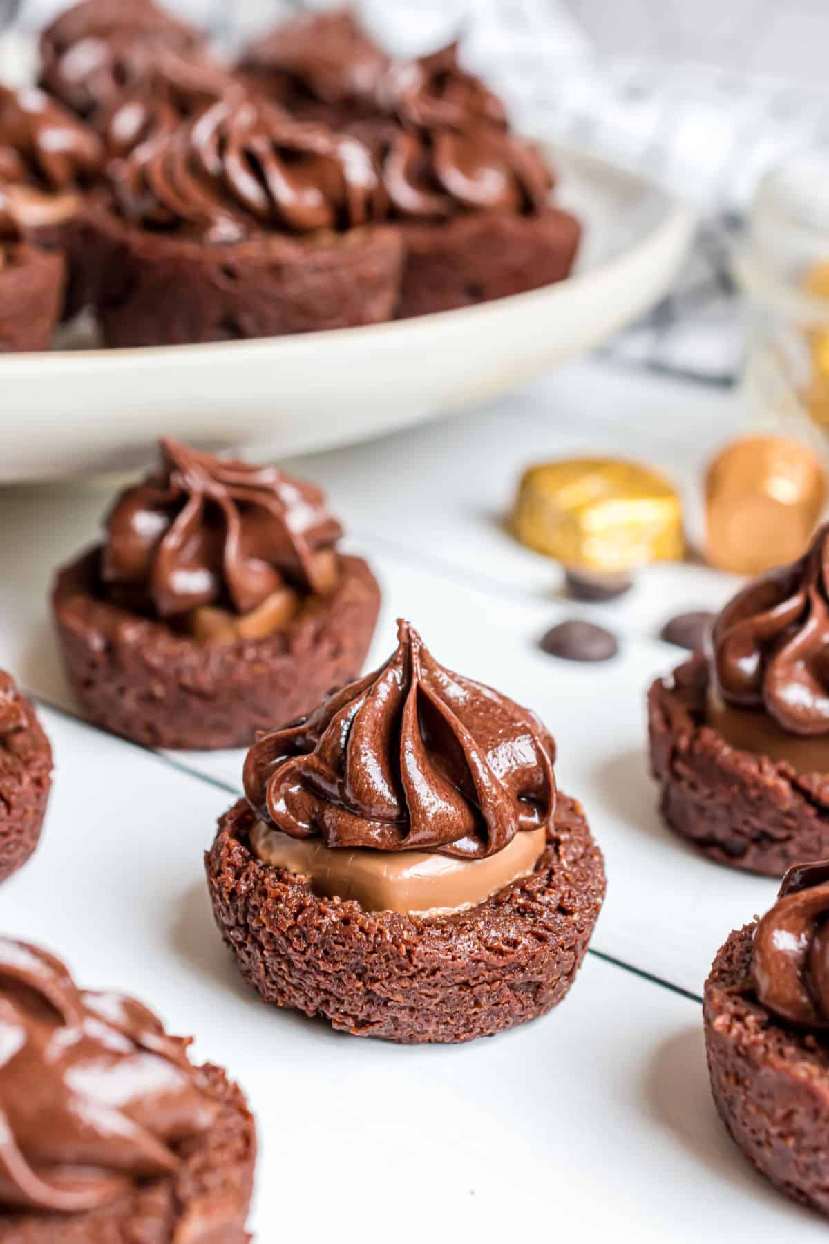 Brownie bites topped with caramel and chocolate frosting.