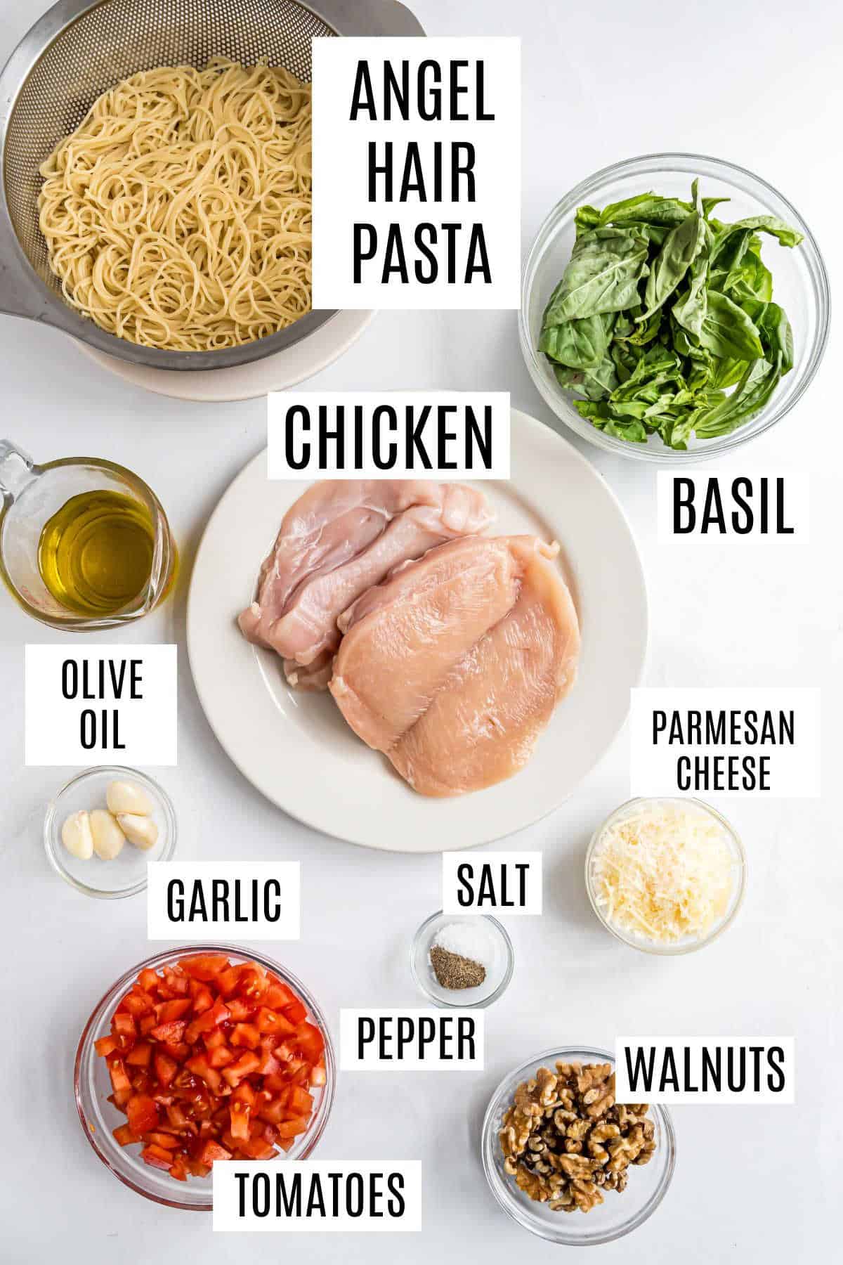 Ingredients for chicken pesto pasta: uncooked angel hair pasta, raw chicken, basil, olive oil, garlic, tomatoes, cheese, and walnuts.