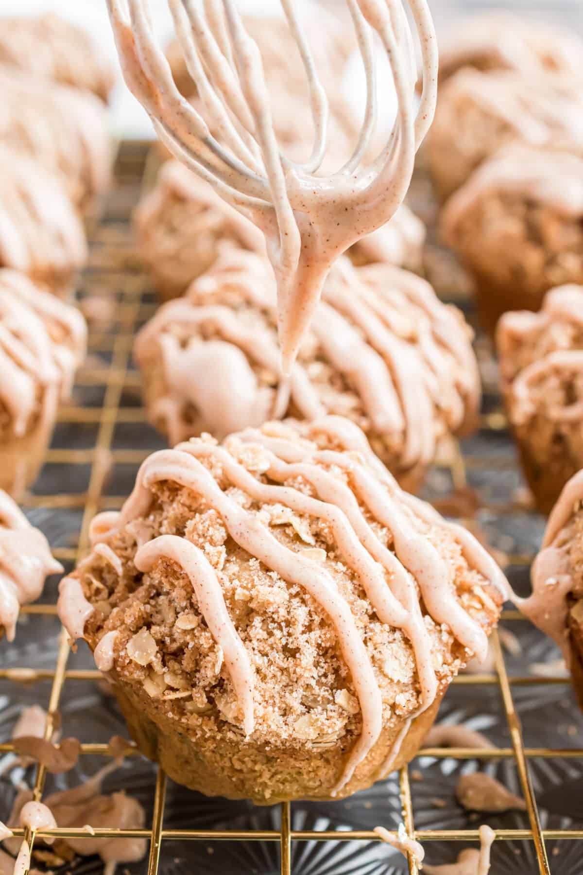 Cinnamon icing being drizzled on muffins with a whisk.