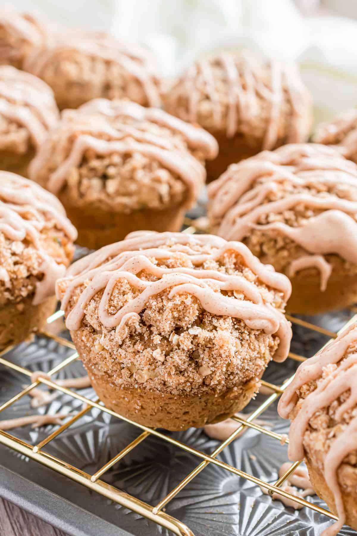 Zucchini muffins with streusel and cinnamon icing on wire cooling rack.