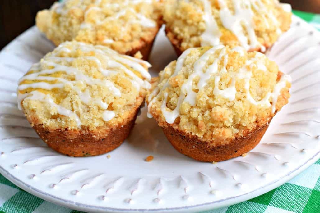 Four lemon muffins on a white plate.